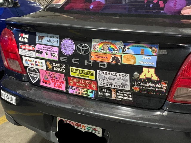 Car trunk with various stickers on a black Toyota Echo