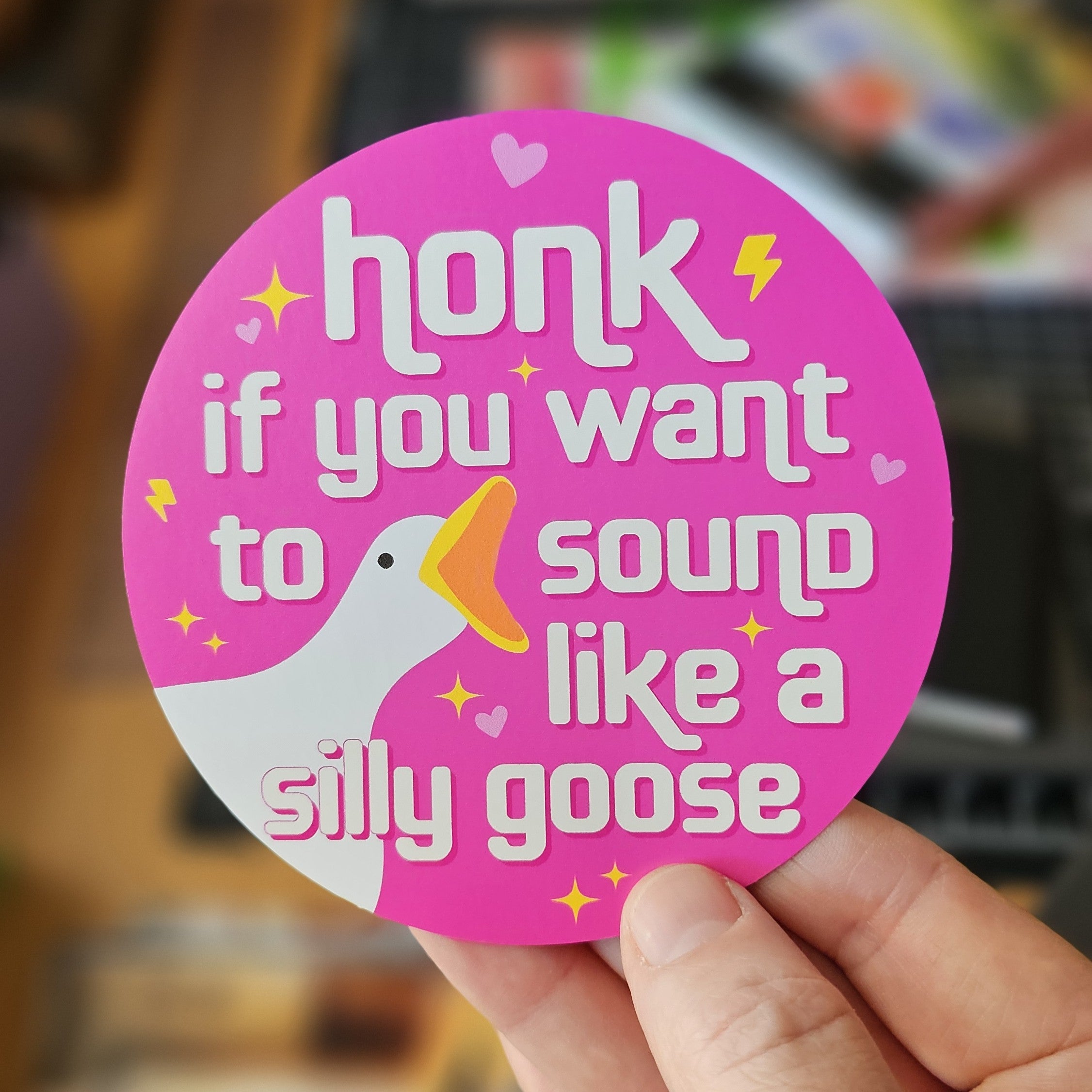 round vinyl sticker, pink, with a goose face and the phrase “honk if you want to sound like a silly goose.”
