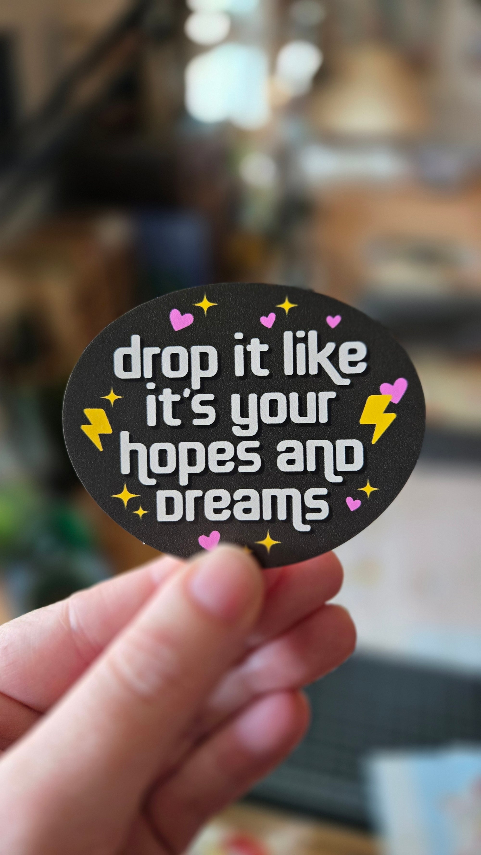 round vinyl sticker options on black with the phrase “drop it like it’s your hopes and dreams,” plus hearts, sparkles, and lightning bolts.
